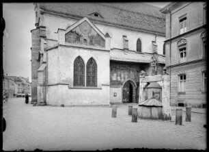 Passau (vermutlich). Rückansicht einer Kirche mit Fassadengemälde und einem Ziehbrunnen mit Skulpturen, Übertragung des heiliges Mirakels