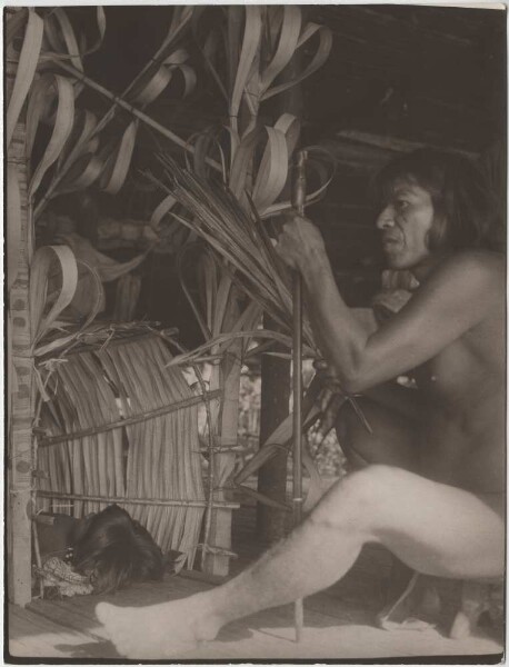 The medicine man Selimo is sitting by a medicine hut in which a sick little girl is lying.