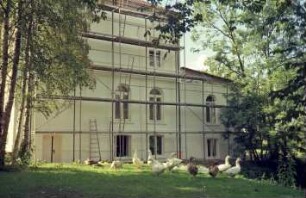 Dorfstraße 45: Hof Mönkhagen: Gutshaus: bei Restaurierung: Seitenfront, rechts rückwärtiger Querflügel: davor Gerüst, Leitern: Neuanstrich