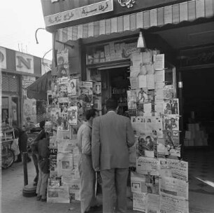Zwei Männer an einem Kiosk mit Auslage internationaler Presse vermutlich in Damaskus