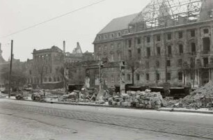 Blick über Gebäudereste, gestapelte Steine und Gleisanlagen der "Trümmerbahn" mit Muldenkipploren gegen Ruine der Reformierten Kirche und Neues Rathaus