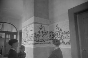Dekorative Ausgestaltung der Klassenräume und Schulflure in der Einheitsschule Baumschulenweg und Oberschule Niederschöneweide in Vorbereitung des Deutschlandtreffens der Jugend für Frieden und Völkerfreundschaft zu Pfingsten 1950 : Schüler vor einem Plakat zum Deutschlandtreffen an einer Wand im Hausflur einer Schule
