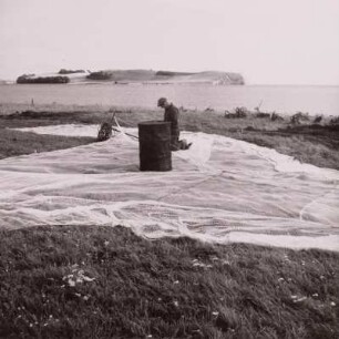 Fischer beim Netze teeren am Strand bei Groß Zicker mit Blick auf die Halbinsel von Klein Zicker / Mönchgut, um 1960