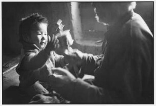 Ladakh. Spielendes Kind mit einer Gebetsmühle und Opa