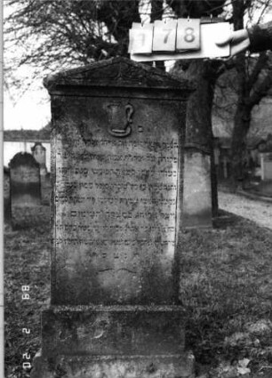 Grabstein 178 (Index: 99798616) Material: Sandstein Zustand: leicht verwittert Maße HxBxT: 126x48x9 cm Beschreibung: Stele mit Giebelabschluß, Sockel Symbolik: Kanne in Schale: Grabstein 178