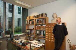 Porträt Perk Loesch, Fachreferent der SLUB : Porträt des Kunstwissenschaftlers Perk Loesch, Fachreferent und von 1996 bis 2019 Leiter der Handschriftenabteilung an der Sächsischen Landesbibliothek – Staats- und Universitätsbibliothek Dresden (SLUB). Aufnahme in seinem Dienstzimmer mit Büste Karl Christian Friedrich Krause (1815)
