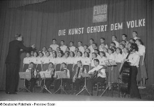 Chor, Orchester sowie Chorleiter bein einem Auftritt beim Kreisausscheid für Volkskunst