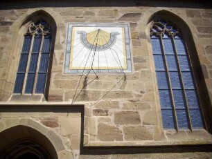 Langhaus Traufseite Süd - Sonnenuhr über Portal zwischen zwei gotischen Fenstern mit Maßwerk