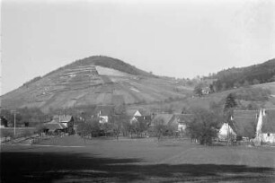 Kulturlandschaft : Dorf am Fuße eines Hügels, an dessen Hängen Landwirtschaft betrieben wird.