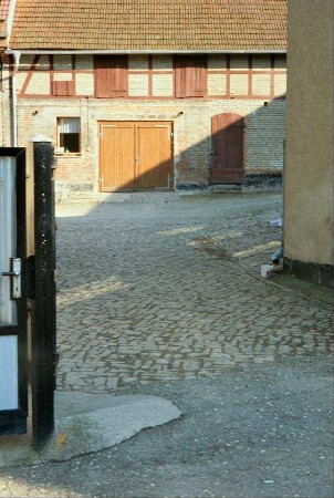 Blick in einen Bauernhof, Kalksteinpflaster, hinten Scheune