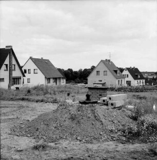 Neubausiedlung: Einfamilienhäuser nach Fertigstellung: im Vordergrund Erdhaufen und Baumaterial