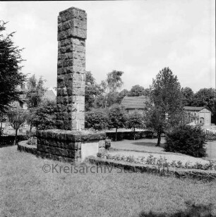 Dorfplatz: Ehrenmal mit Anlage: dahinter Gasthof und Bäume