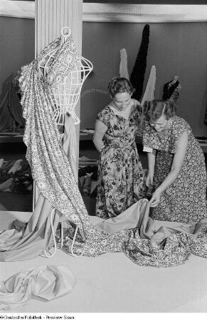 Zwei Frauen begutachten Textilien der Leipziger Herbstmesse 1954
