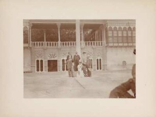 Gruppenportrait : Portraitaufnahme von einer Frau mit Kind und fünf Männern in einem Innenhof in Bagdad. Rechts vorne der Geograph Hugo Grothe (1869-1954).