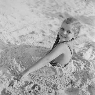 In Sand eingegrabenes Mädchen am Strand