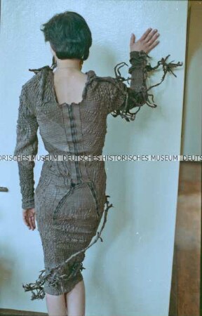 Modell in einem braunen Lederkleid (Rückseite) der Designergruppe Allerleirauh