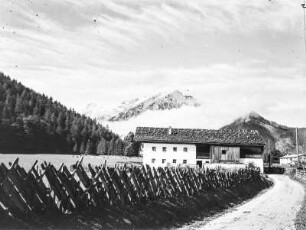 Gehöft : Blick entlang eines umzäunten Weg zu einem Gehöft. Im Hintergrund ein Gebirge