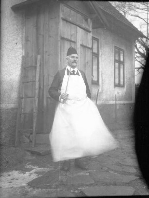Mann mit Schürze im Garten eines Hauses