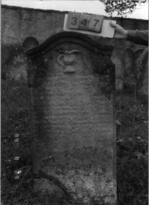 Grabstein 347 (Index: 100107790) Material: gelber Sandstein Zustand: stark verwittert, völliger Textverlust Maße HxBxT: 130x64x20 cm Beschreibung: Stele mit geschwungenem Bogenabschluß, profilierte Verdachung, Levitenkanne Symbolik: Levitenkanne: Grabstein 347