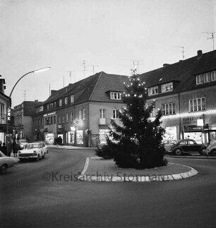 Besttorstraße Ecke Bahnhofstraße: Tannenbaum mit Adventsbeleuchtung auf der Verkehrsinsel, parkende Pkw, im Hintergrund Gebäude mit Adventbeleuchtung der Bahnhofstraße, Blick Richtung Südwesten