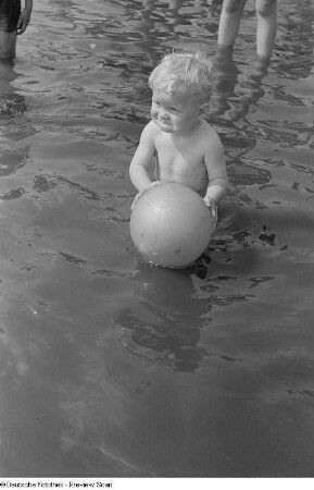 Kleiner Junge mit einem Ball, im Wasser spielend