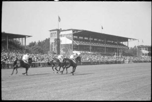 Hoppegarten: Pferde im Galopp vor den Tribünen [mit Hakenkreuzfahne]