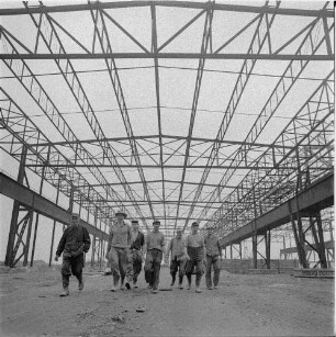 Zeithain. Baustelle Rohrwerk III des VEB Stahl- und Walzwerk Riesa. Produktionshalle (Stahlskelettbau) im Rohbau, im Vordergrund eine Gruppe Bauarbeiter