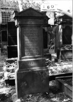 Grabstein 160 (Index: 100094299) Material: Sandstein Zustand: gut Maße HxBxT: 164x59x35 cm Beschreibung: kon. Stele, profiliert. Sock, Giebel mit stilisiert. Eckakrot, Schriftfeld eingetieft: Grabstein 160