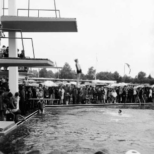 Sommerbad Tarpenbek: Am Hallenbad: Eröffnung: Person springt vom Sprungturm, Gäste am Rand des Schwimmbeckens
