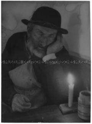 Schlafender Bauer am Tisch mit Kerze