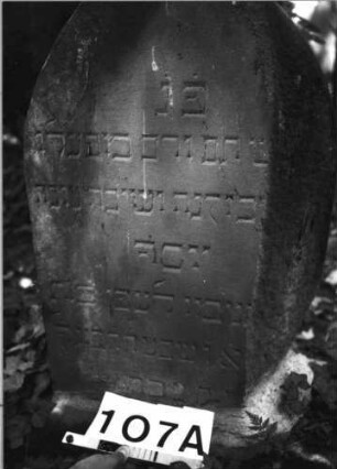 Grabstein 107 (Index: 100085527) Zustand: rechter Teil Rückseite weggebrochen Maße HxBxT: 75x50x23 cm Beschreibung: Stele, Sockel, Spitzbogenabschluß, Schriftfeld eingetieft auf Vorderseite: Grabstein 107A