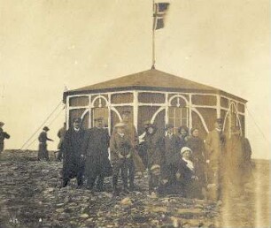 Nordkap. Touristen vor dem Postamt (mit Champagnerausschank) mit norwegischer Flagge