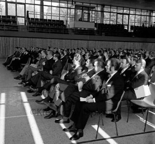 Gemeinnützige Wohnstättengenossenschaft eGmbH: 75-jähriges Jubiläum: Stormarnhalle: Blick auf Gäste und Mitglieder in Sitzreihen: in vorderer Reihe Ehrengäste, darunter Vorsitzender des Aufsichtsrats Heinz Sonnenberg, Präsident des Verbands norddeutscher Wohnungsunternehmen e.V. Joachim Teske, Bürgermeister Gottfried Baethge, Landesminister für Soziales Karl Eduard Claussen, die Bundestagsabgeordneten Werner Zywietz (FDP) und Friedrich Beermann (SPD), 24. März 1973