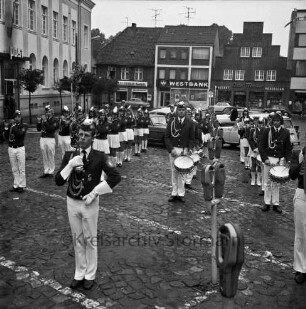 Oldesloer Spielmannszug e.V.: Markt: Entgegennahme der Standarte: Spielmannszug spielt: Parkuhren: links Postgebäude: hinten rechts an Hindenburgstraße Wohn- und Geschäftshaus, darin "Kleiderbad Buchholz", "Westbank"