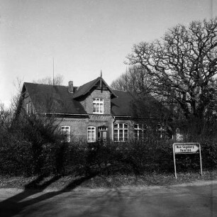 Steinfeld: Kreisstraße Richtung Reinfeld: vorn rechts Straßenschild: dahinter Wohnhaus [ehemalige Volksschule] mit Garten und Hecke: hinten rechts Baum