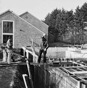 Volksschule: Soltausredder: Erweiterungsanbau: vorn rechts Grundmauern und Holzverschalungen: in der Mitte und links auf Brett Arbeiter: links Baumaterial: dahinter Schulgebäude: hinten rechts Bäume