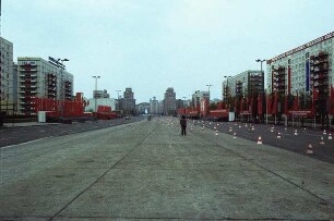 Berlin. Karl-Marx-Allee vermutlich während der Vorbereitung auf die Demonstration zum Ersten Mai. Ansicht mit Tribüne, Beflaggung und Spruchbändern