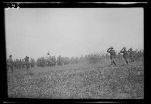 Bei Focșani (Rumänien): Vorbeimarsch von Soldaten mit Stahlhelm und geschultertem Bajonett an einer Gruppe von Offizieren mit Pickelhaube auf einem weiten Feld (Distanzaufnahme) ("Kaiserparade")