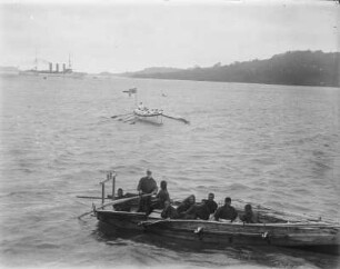 Ruderboot : Blick auf ein vollbesetztes Ruderboot, dahinter ein Boot mit Marinesoldaten