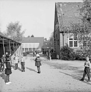 Volksschule: Soltausredder: vorn Schulhof mit Schulkindern: rechts Altbau mit Sträuchern: links Unterstand: hinten Turnhalle: davor Lieferwagen