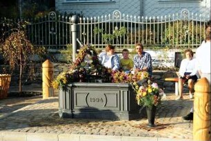 Brunneneinweihung; Menschen auf einer Bank am neuen Brunnen