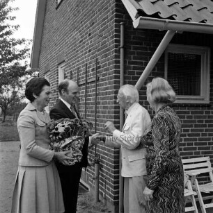 Hermann Claudius: Schriftsteller: geboren 19. Oktober 1878, gestorben 8. September 1980: 100. Geburtstag: vor Wohnhaus: Jubilar mit Ehefrau Gisela Claudius bei Begrüßung der Gratulanten Landesminister für Justiz Henning Schwarz und Ehefrau Gertrud Schwarz, mit Blumenstock: Klappstühle, 19. Oktober 1978