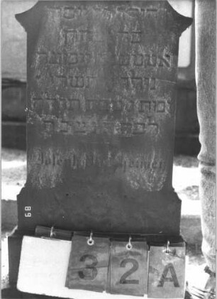 Grabstein 32 (Index: 100105720) Material: Sandstein Zustand: sehr stark verwittert Maße HxBxT: 87x37x8 cm Beschreibung: Stele, Sockel auf Rustica, Abschluß Sonderform Symbolik: sechszackiger Stern und florales Motiv Besonderheit: Kindergrab: Grabstein 32A (Nachholaufnahme)