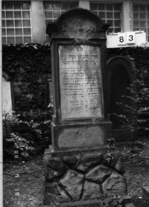 Grabstein 83 (Index: 100094778) Material: Sandstein, weiße Marmorplatte Zustand: verwittert und beschädigt Maße HxBxT: 169x69x40 cm Beschreibung: St, getreppt. Sock, unten rustica, eingezog. Rundbogenabschl. m. Verdach, rechteck. Platt: Grabstein 83