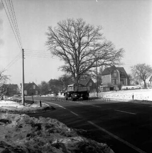 Stormarnstraße: Bundesstraße 75: in der Mitte Lkw: dahinter Baum: links Strommast: im Hintergrund Wohn- und Bauernhäuser: Winter