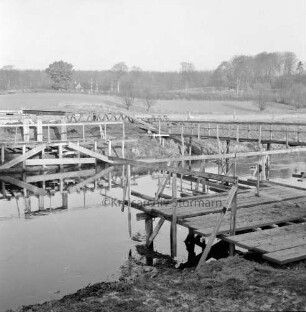 Trave: Spannbetonbrücke: Neubau: am Ufer Holzgerüste für das Setzen der Betonpfeiler: hinten rechts alter Notsteg: hinten Kneeden