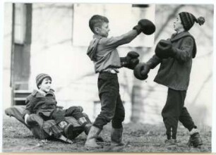 Zwei Jungen beim Boxkampf mit einem Zuschauer