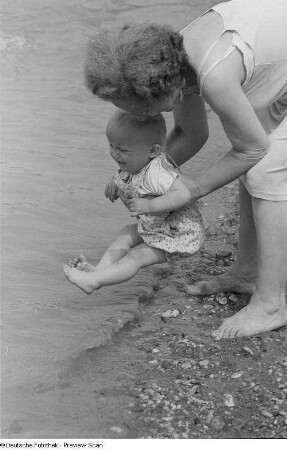 Frau mit einem Kleinkind am Ufer