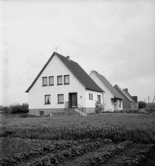 Neubausiedlung: Einfamilienhäuser: vorn Wiese und Gartenbeete