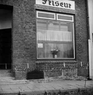 Friseursalon: Hamburger Straße: Schaufenster mit Gardinen und Blumenvase: darüber an Hauswand Inschrift: links Eingang: vorn Absperrung